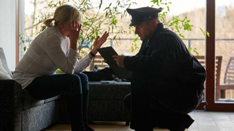 Police officer crouching down to talk to seated woman