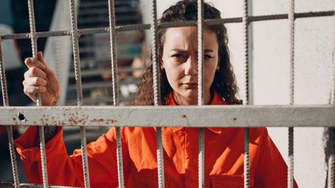 Woman in orange behind prison bars