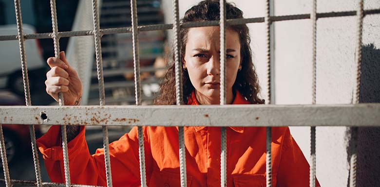 Woman in orange behind prison bars
